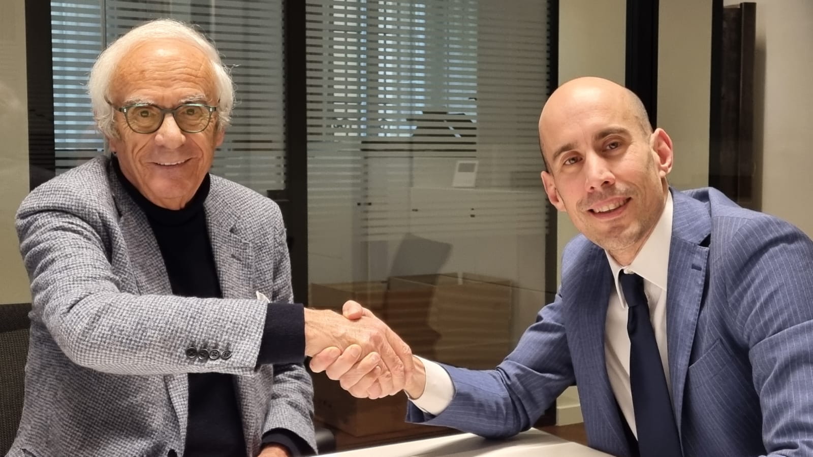 img title Alcide Casini ed Emanuele Ciotti sorridono mentre si stringono la mano a Palazzo Graziani sopra l'atto di donazione ufficiale.
