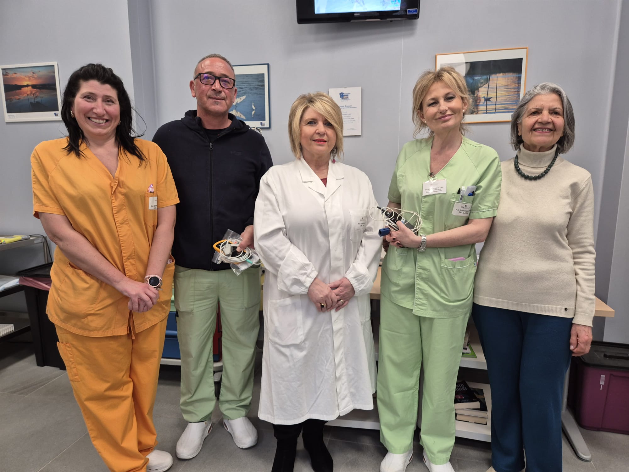 Tre operatrici sanitarie e due volontari mostrano i nuovi dispositivi medici donati al reparto.