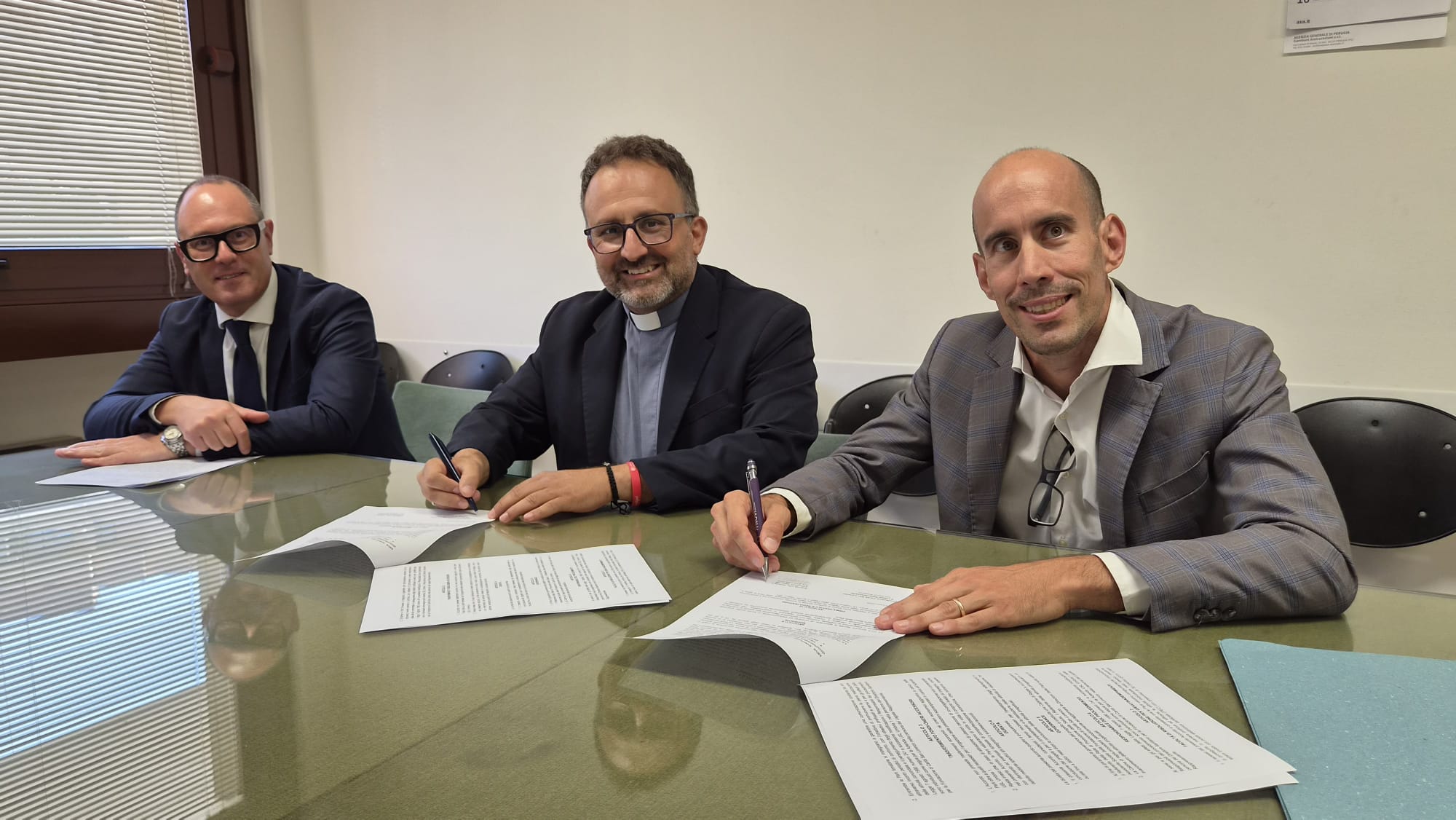 img title Da sinistra, Nicastro, Briziarelli e Ciotti seduti a un tavolo mentre firmano un accordo ufficiale su alcuni documenti cartacei.