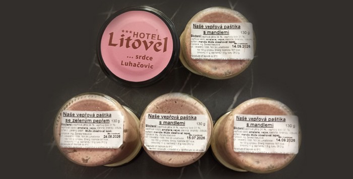 img title Confezioni di paté di maiale oggetto di richiamo sanitario per rischio botulino. In alto a sinistra è presente un coperchio rosa con il marchio 'HOTEL Litovel… srdce Luhačovic'. Gli altri quattro barattoli di vetro da 130g mostrano etichette bianche con le diciture in ceco 'Naše vepřová paštika s mandlemi' (con mandorle) e 'Naše vepřová paštika se zeleným pepřem' (con pepe verde), recanti le date di conservazione 15.07.2026, 24.08.2026 e 14.09.2026