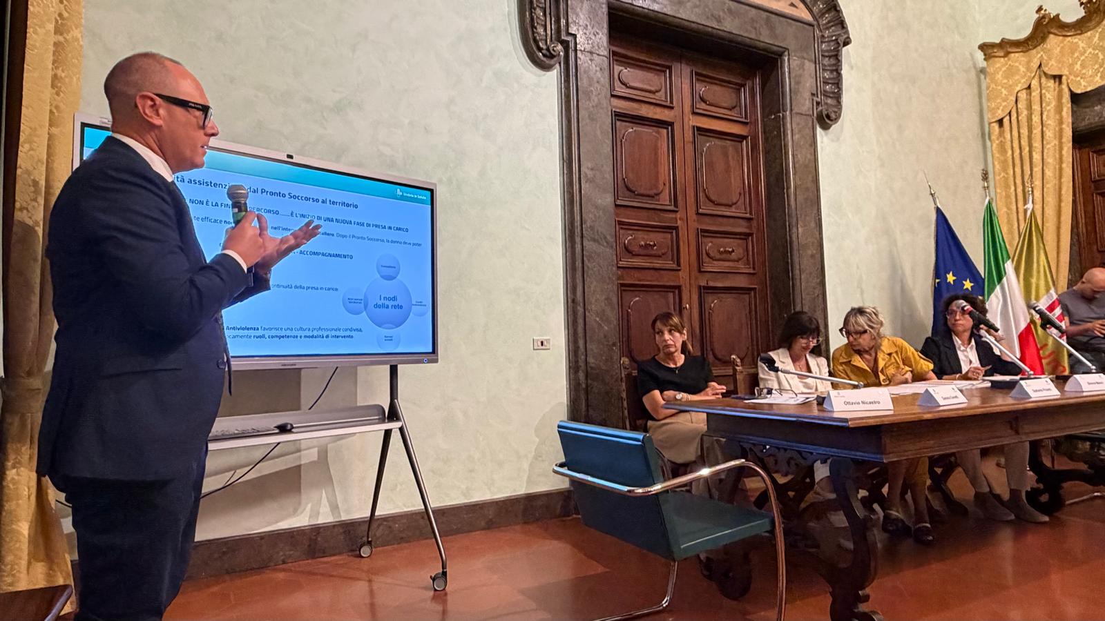 img title Il dottor Ottavio Alessandro Nicastro, direttore sanitario dell'Azienda USL Umbria 1, in abito scuro presenta una slide sulla continuità assistenziale dal Pronto Soccorso al territorio durante una conferenza con tavolo dei relatori.