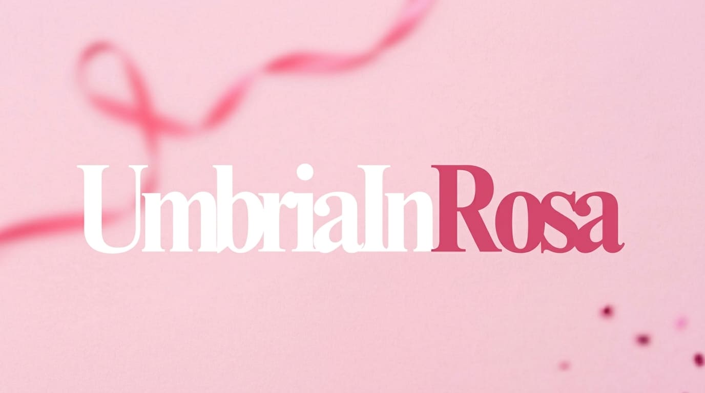 img title Banner grafico orizzontale su sfondo rosa chiaro con la scritta centrale 'UmbriaInRosa' in caratteri bianchi e fucsia. In secondo piano e sfocato s'intravede un nastro rosa simbolo della prevenzione del tumore al seno.