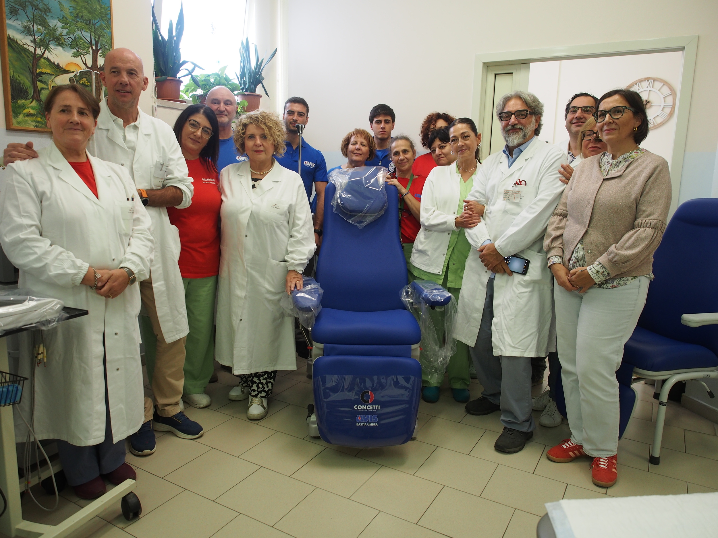 img title Operatori sanitari e volontari posano attorno a una nuova poltrona trasfusionale donata all'ospedale di Assisi.